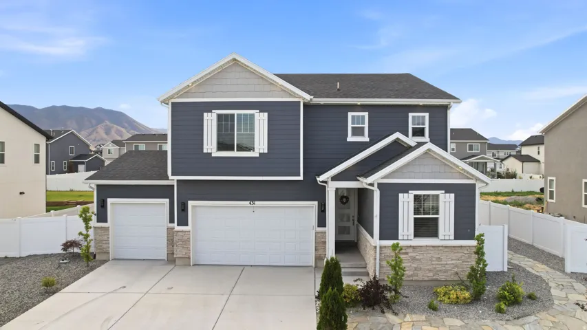Two-story home featuring a dark blue siding exterior, stone accents, and white trim