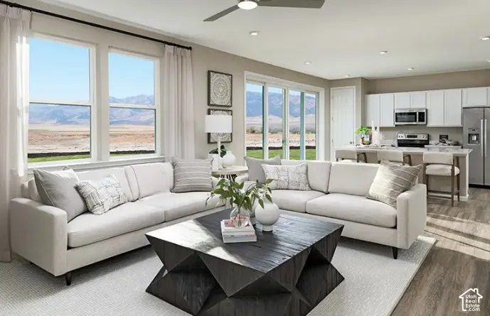 Open-concept living space with large windows, mountain scenery, light wood-finish flooring, and a kitchen island with seating