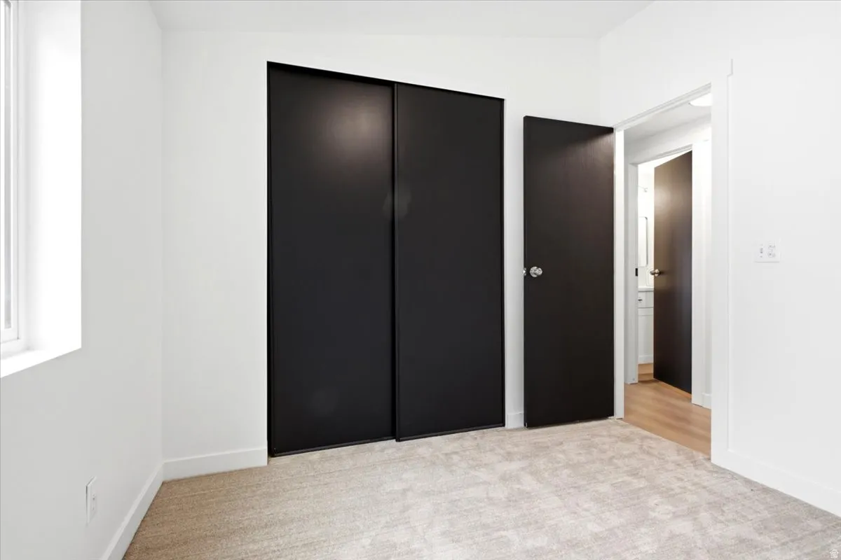 Room featuring light-toned carpeting, white walls, and a window with white trim