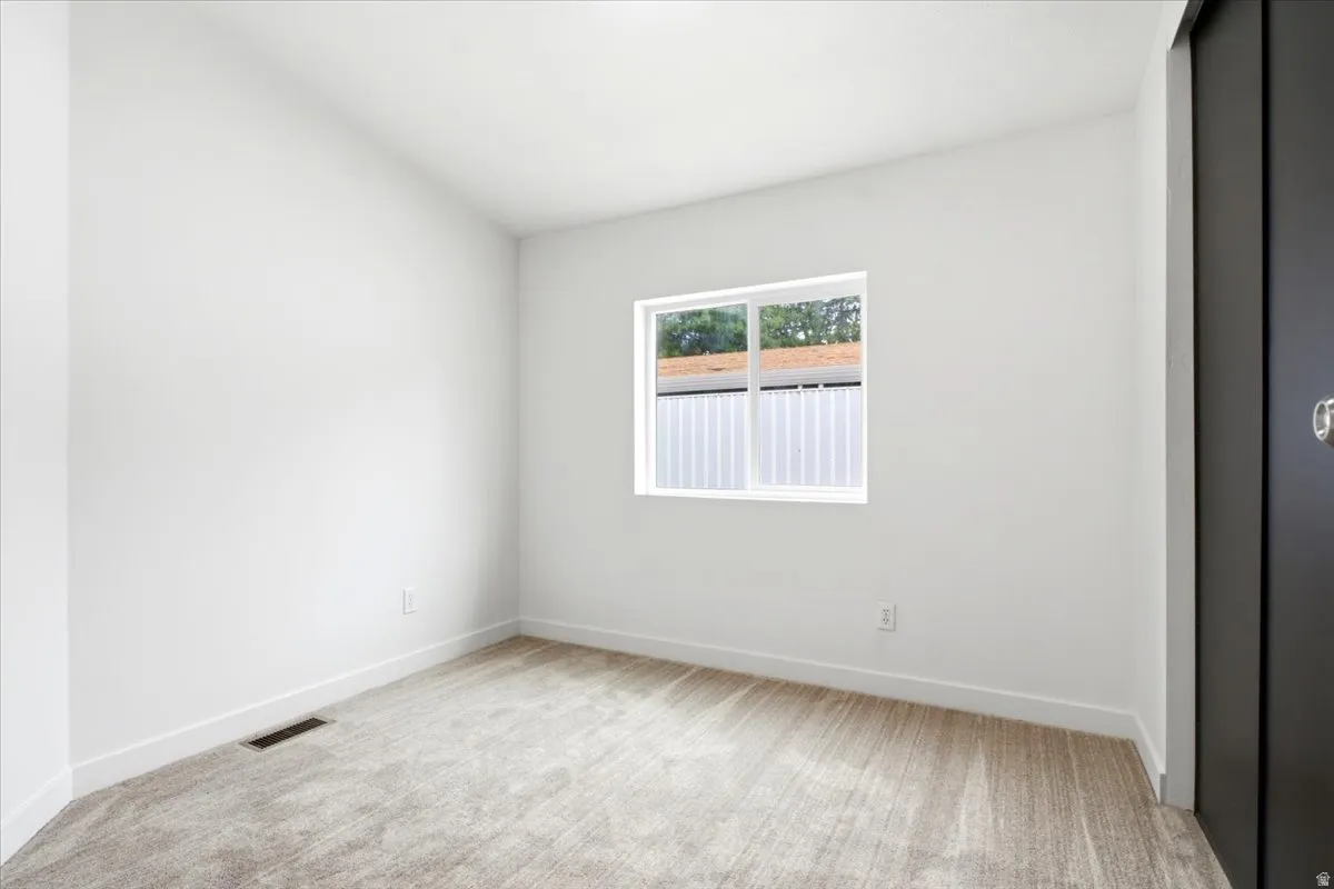 Bright room featuring light-toned carpet, white walls, and a white window frame