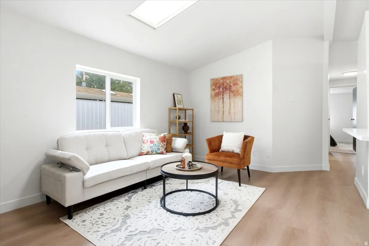 Bright living space featuring a skylight, wide window, and wood-finish flooring
