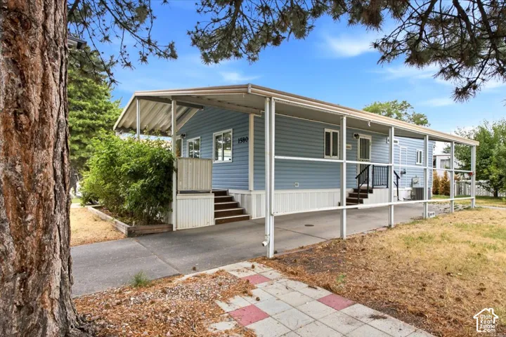 Light blue siding exterior with white trim windows and a covered carport