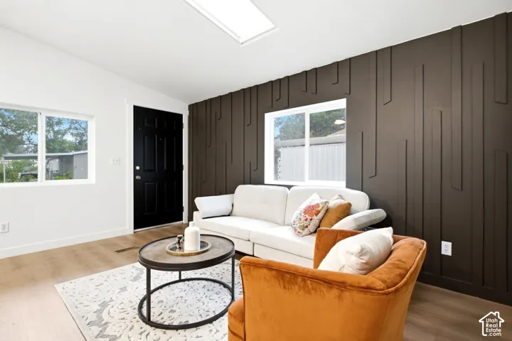 Living area featuring a custom dark-toned geometric accent wall, wood-finish flooring, skylight, and dual-pane windows