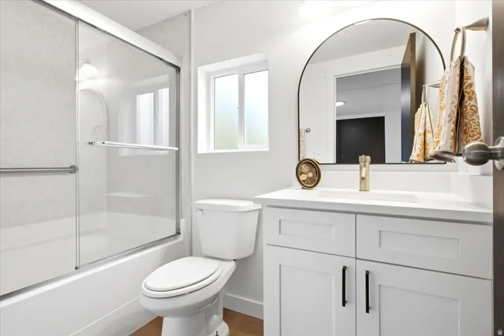 Contemporary bathroom featuring a white vanity with shaker-style cabinetry, a drop-in sink, and a gold-tone faucet