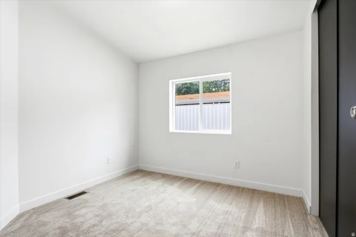 Bright room featuring light-toned carpet, white walls, and a white window frame