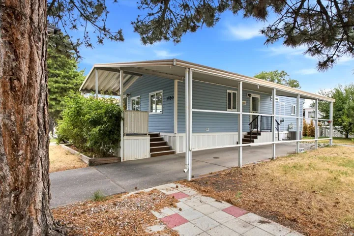 Light blue siding exterior with white trim windows and a covered carport