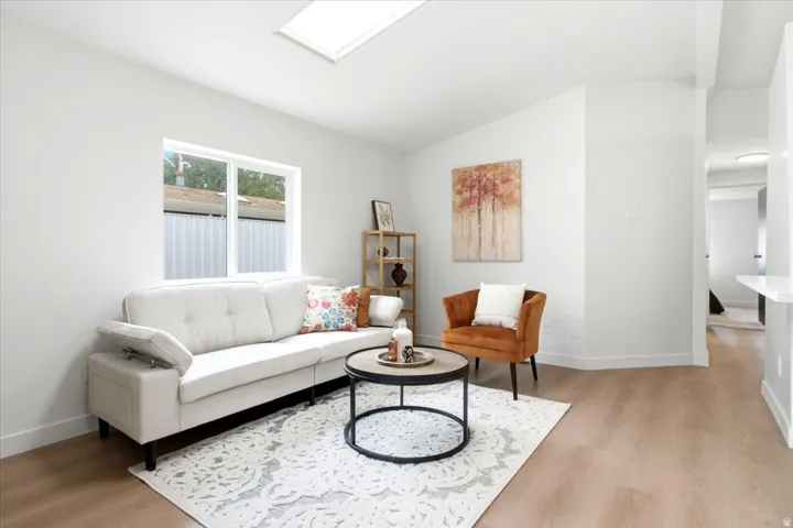 Bright living space featuring a skylight, wide window, and wood-finish flooring