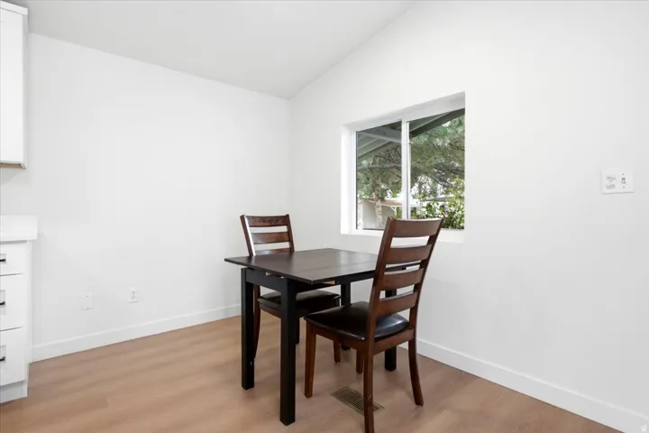 Bright interior space featuring a single window, white walls, and wood-finish flooring