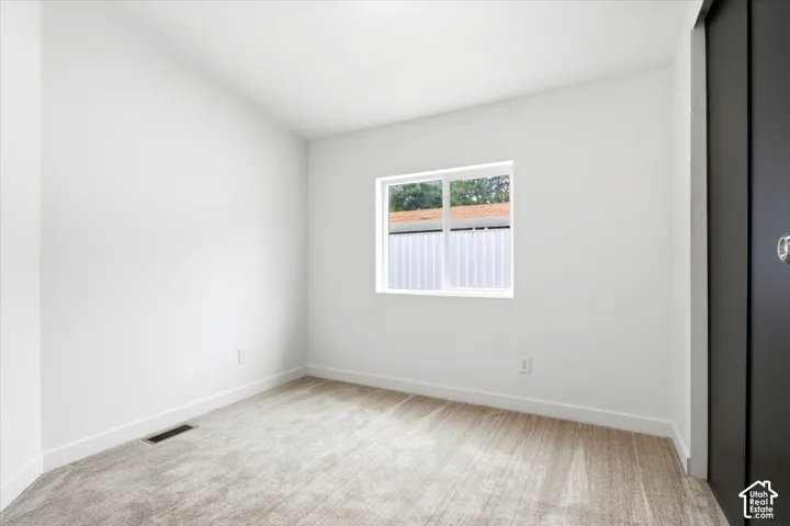 Bright room featuring light-toned carpet, white walls, and a white window frame