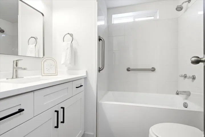 Bathroom featuring a white vanity with black hardware, a rectangular undermount sink, and a white countertop