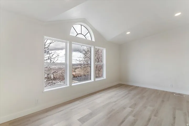 Vaulted ceiling room featuring a large arched transom window above three rectangular windows