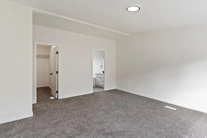 Spacious room featuring gray carpeting, white walls, and a recessed ceiling light