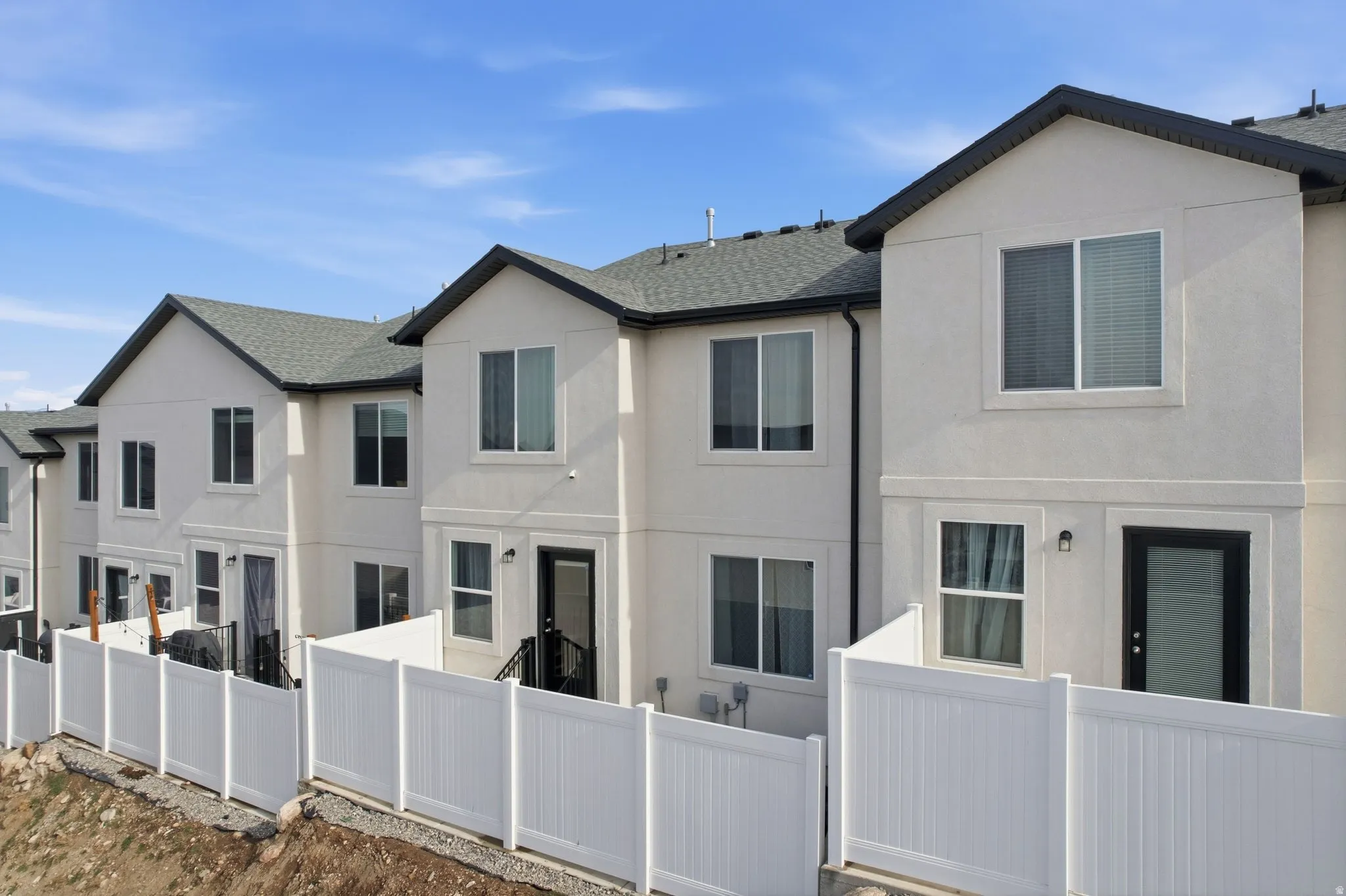Contemporary townhome exterior featuring light-colored siding and dark trim