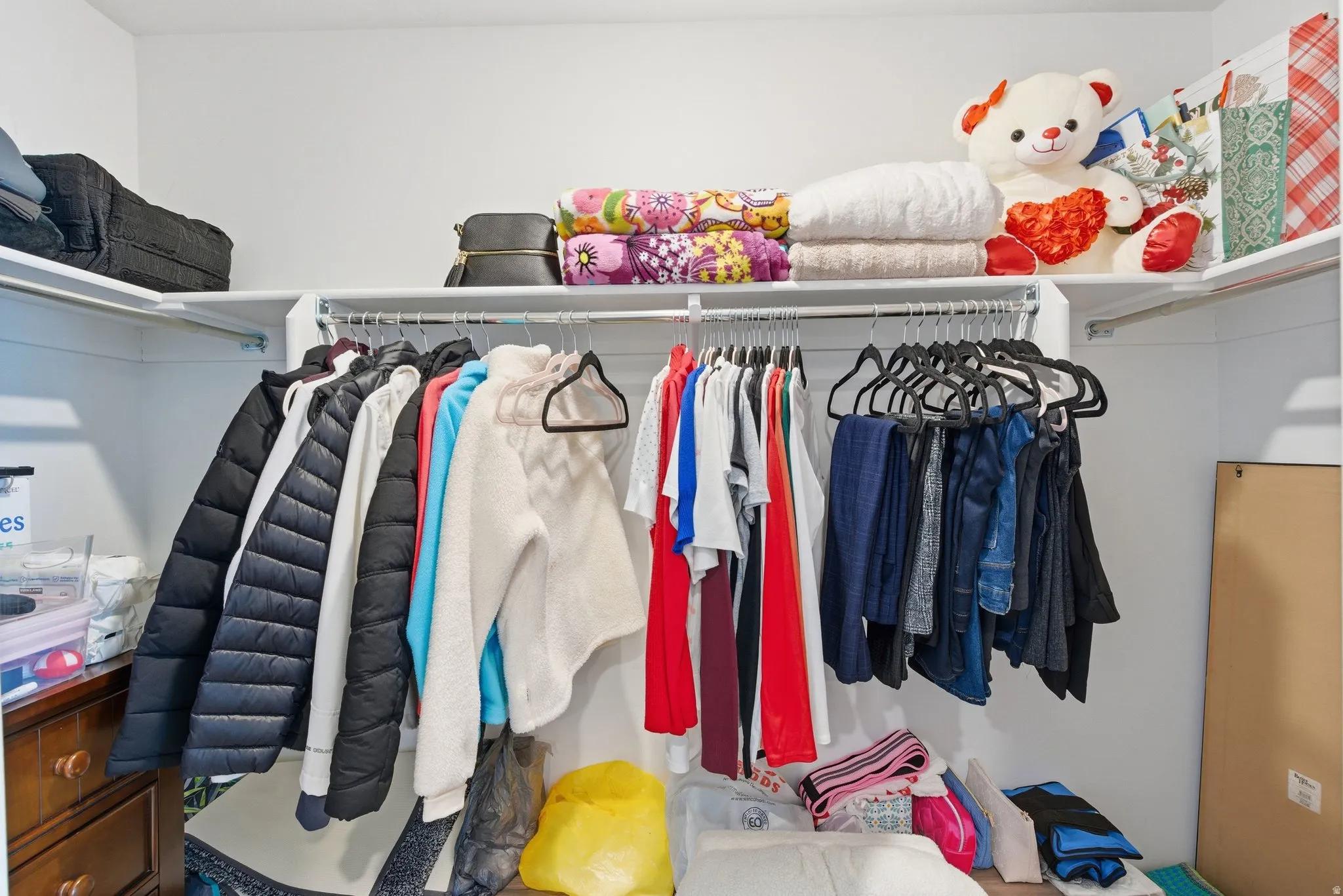 Corner closet featuring white shelving and hanging rods