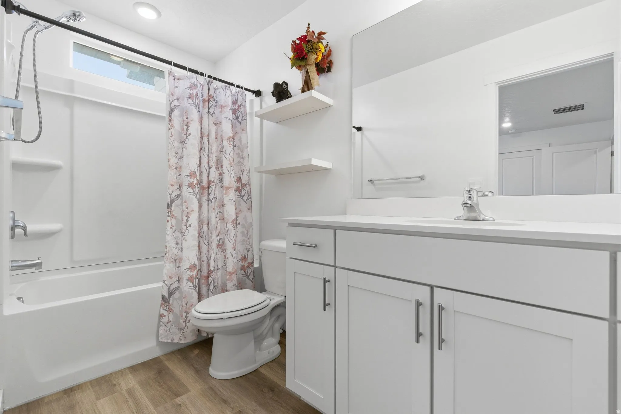 Bathroom featuring a white vanity with an integrated sink, polished chrome faucet, and a large wall-mounted mirror