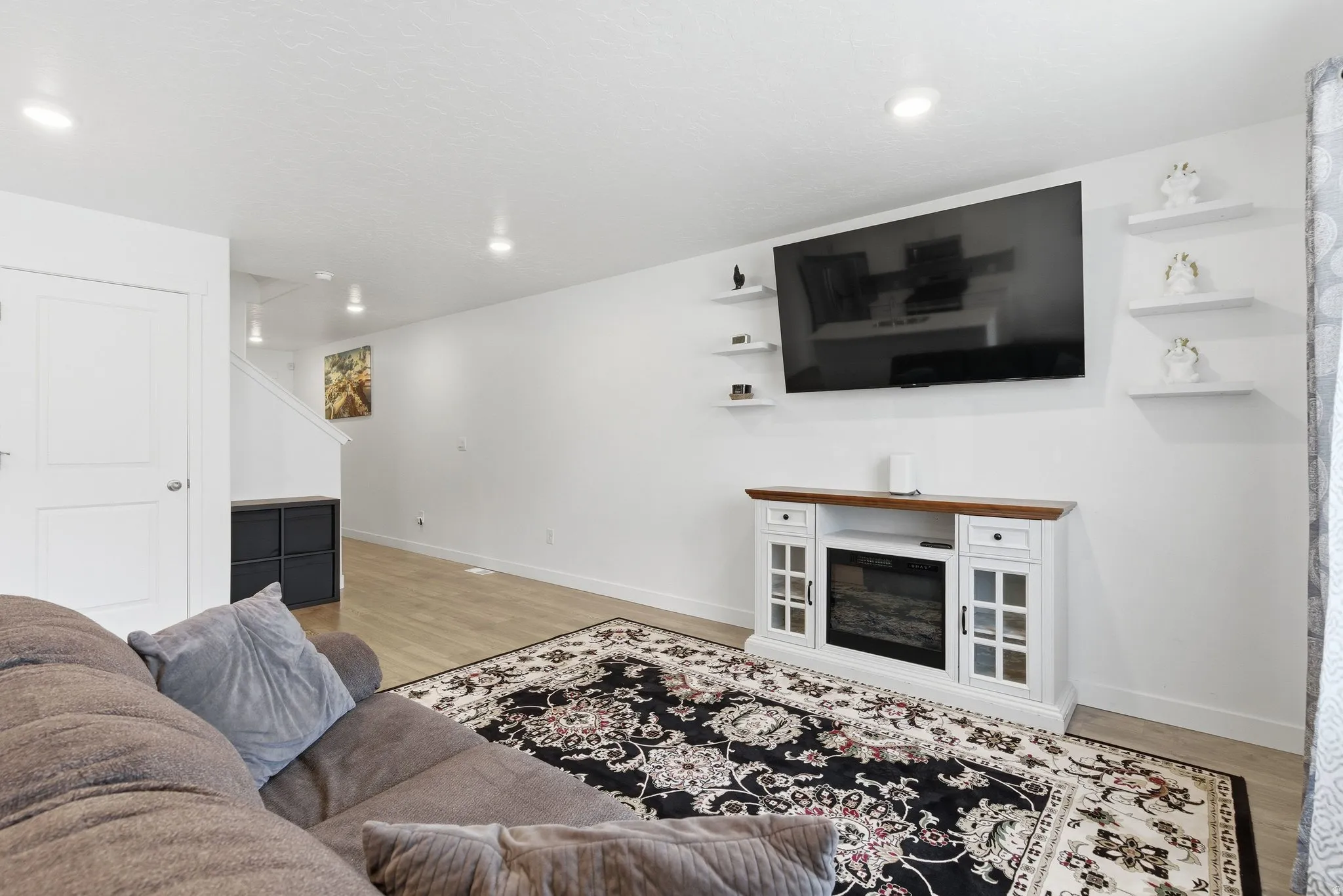 Bright living area featuring wood-finish flooring, recessed lighting, and a white decorative fireplace console with a wooden top