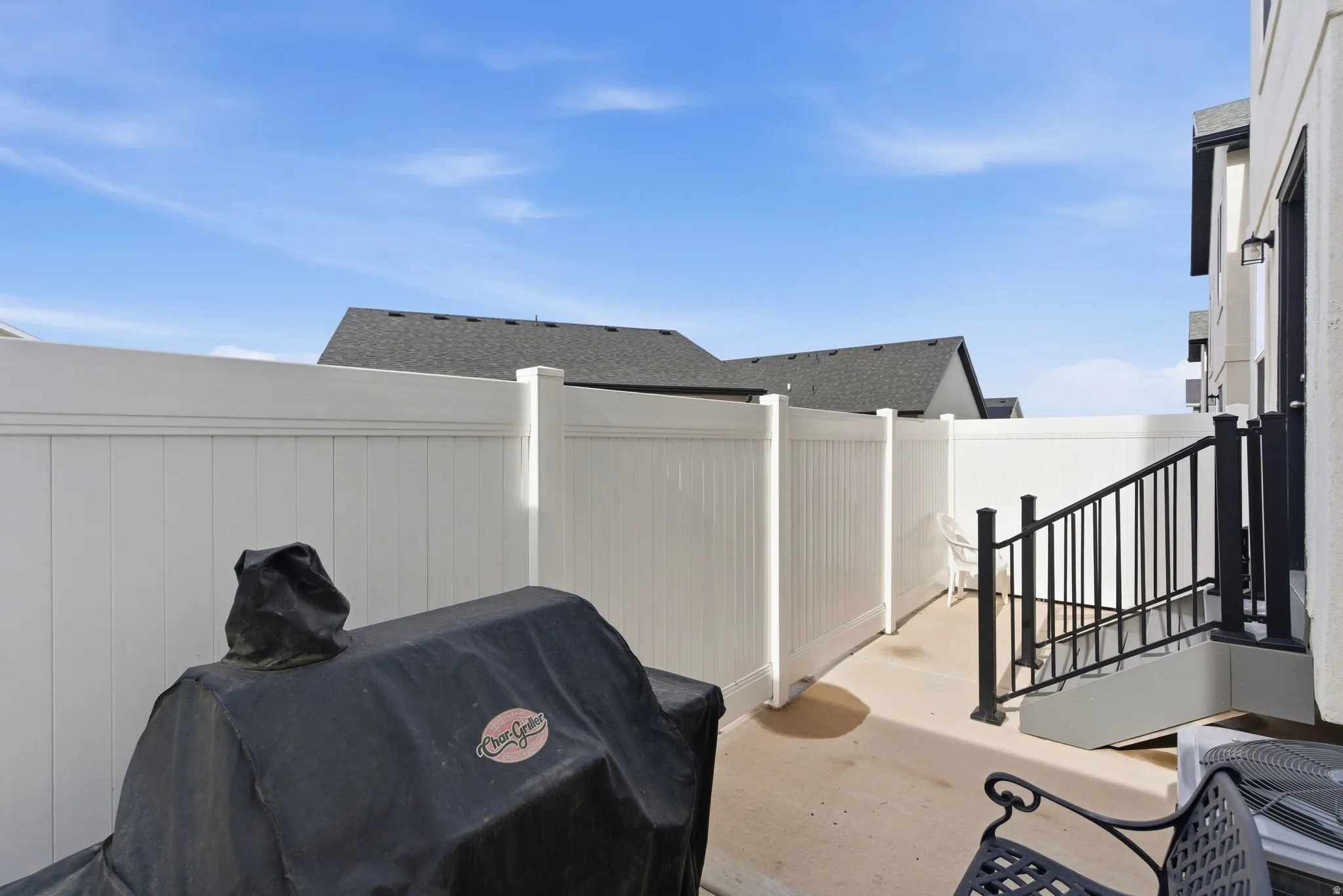 Private patio area with concrete flooring, framed by a white privacy fence