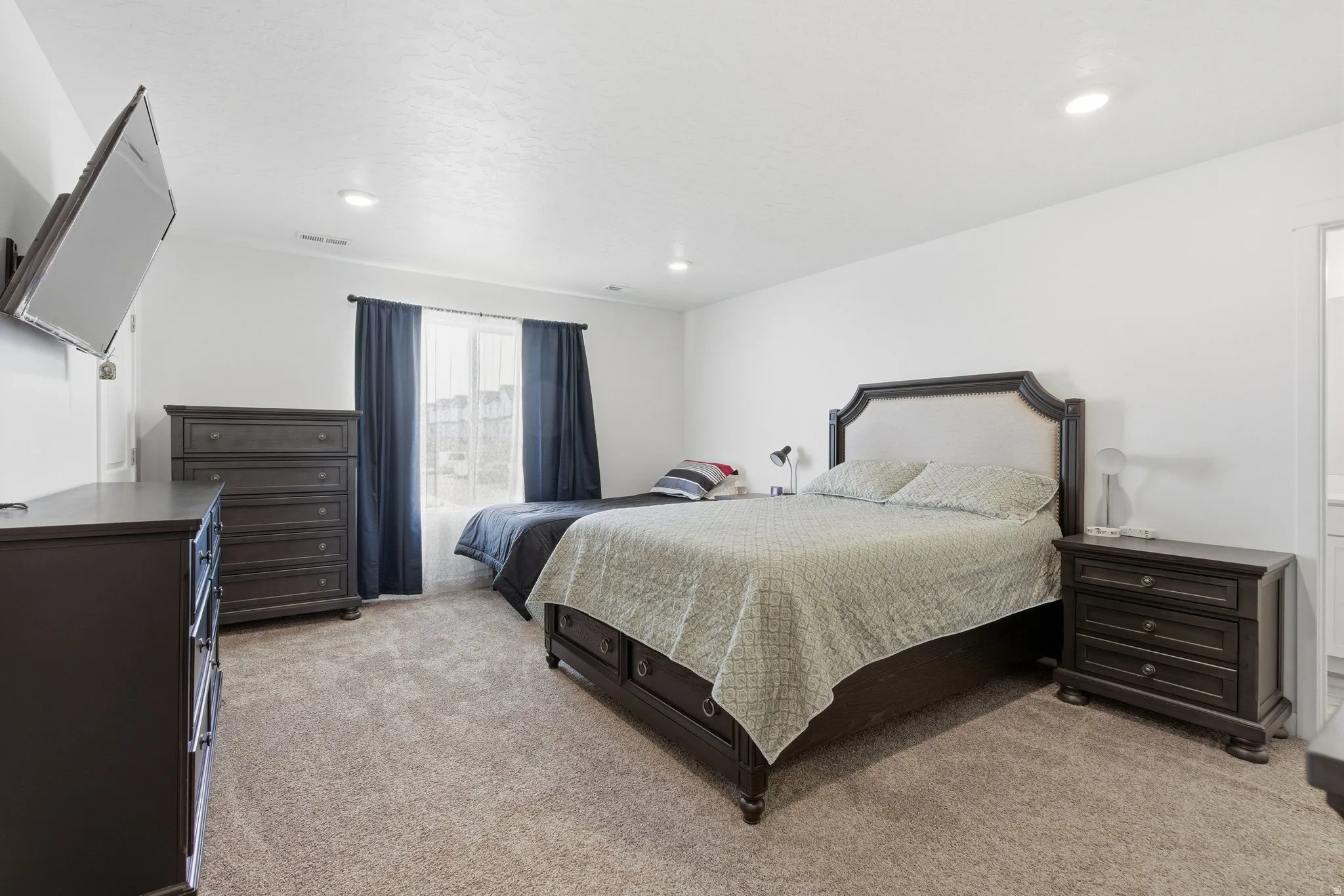 Carpeted room with recessed lighting and a window featuring dark curtains