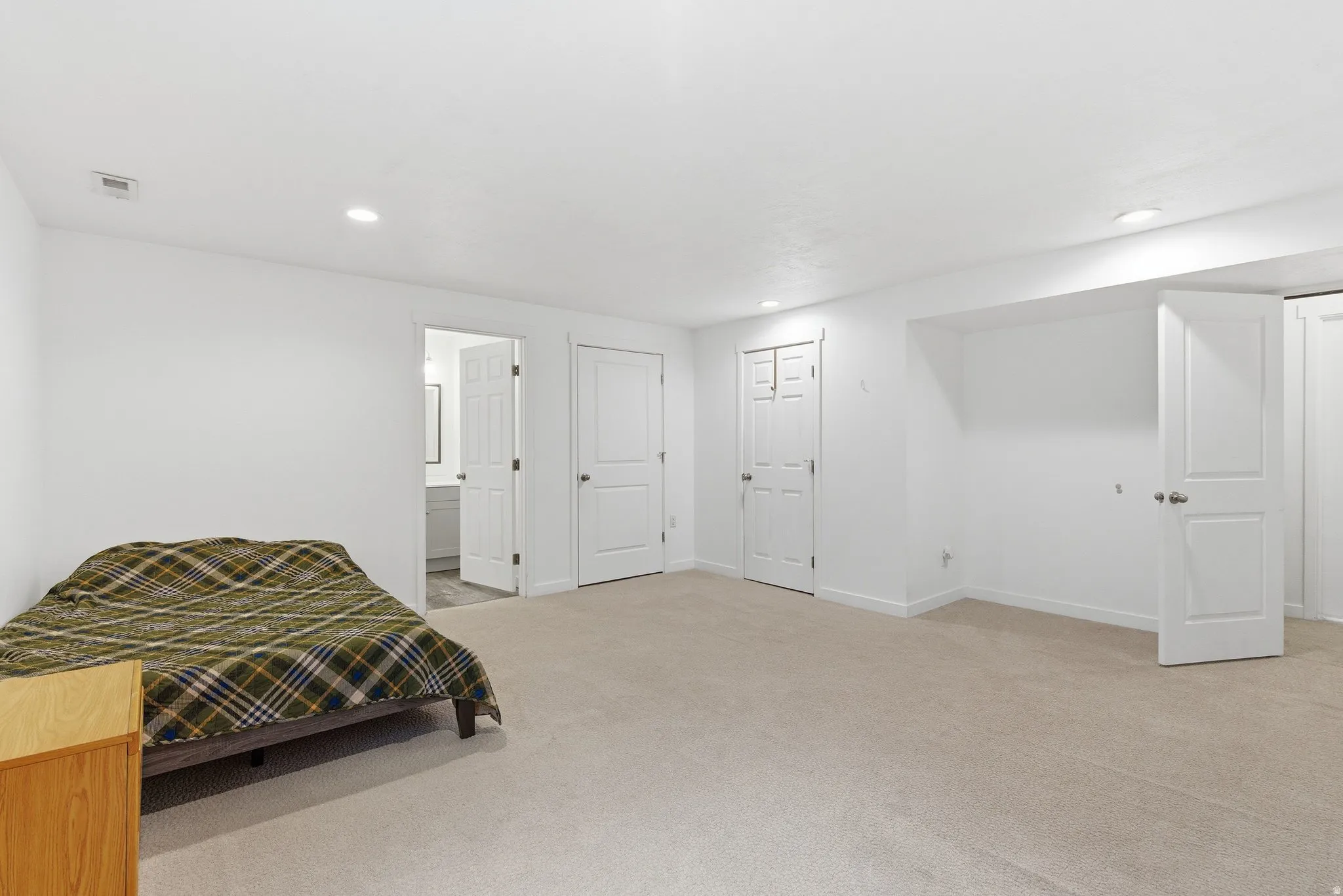 Spacious room featuring neutral carpeting, recessed lighting, and white walls