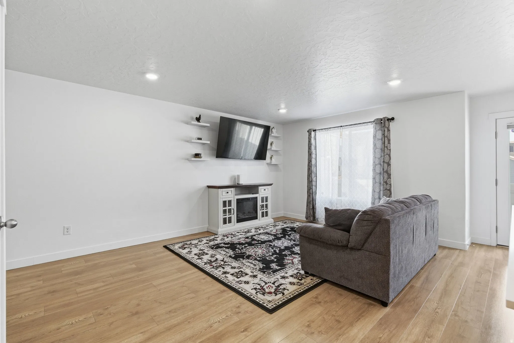 Living area featuring light wood-finish flooring, white walls, and recessed lighting