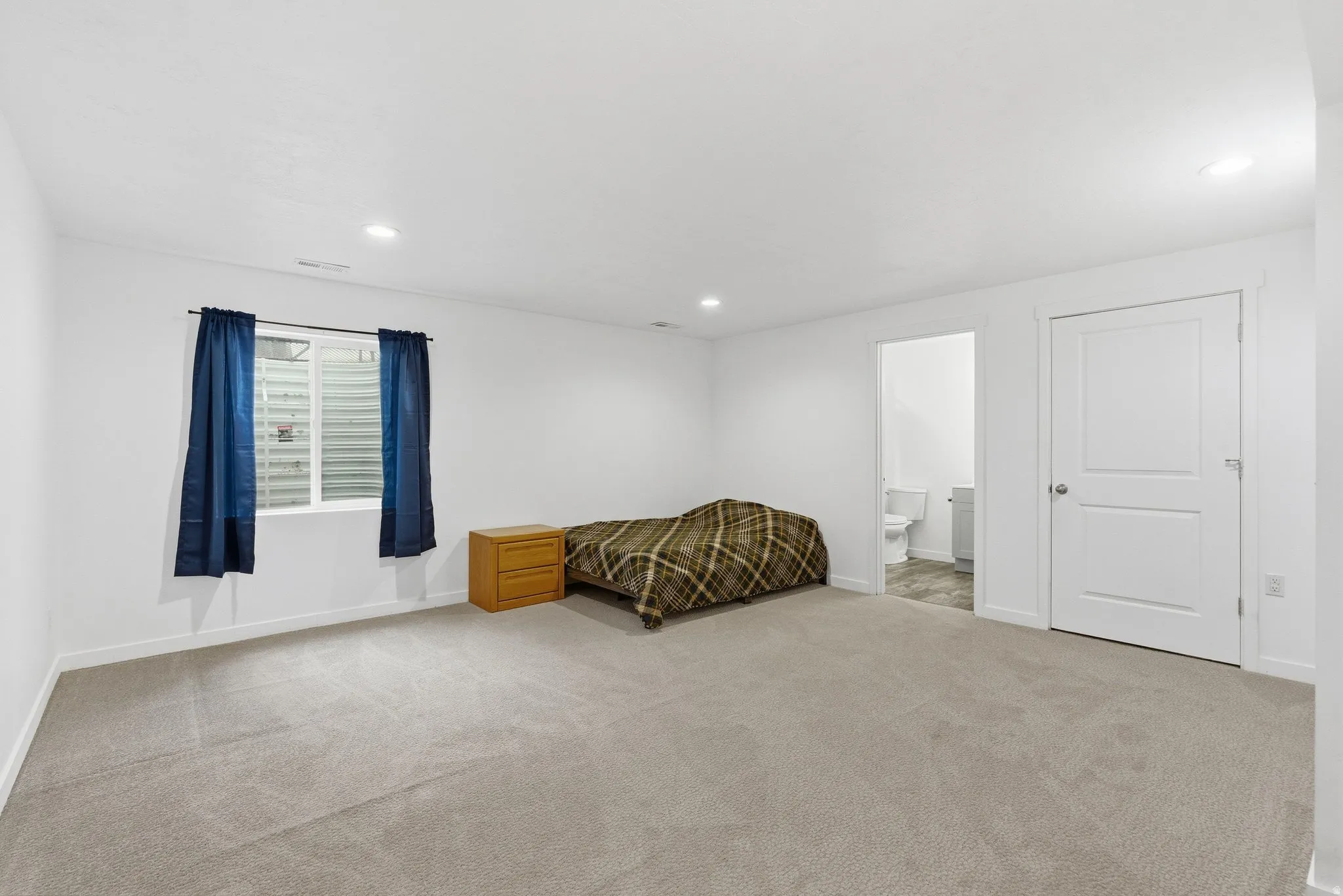 Spacious room featuring light-colored carpeting and white walls