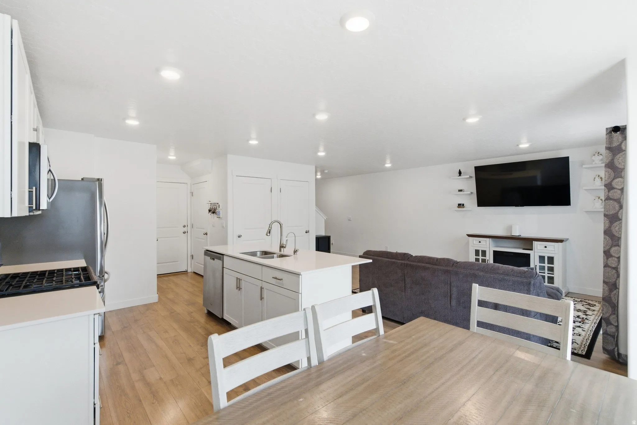 Open-concept living space featuring a central kitchen island with dual sinks, stainless steel appliances, and recessed lighting
