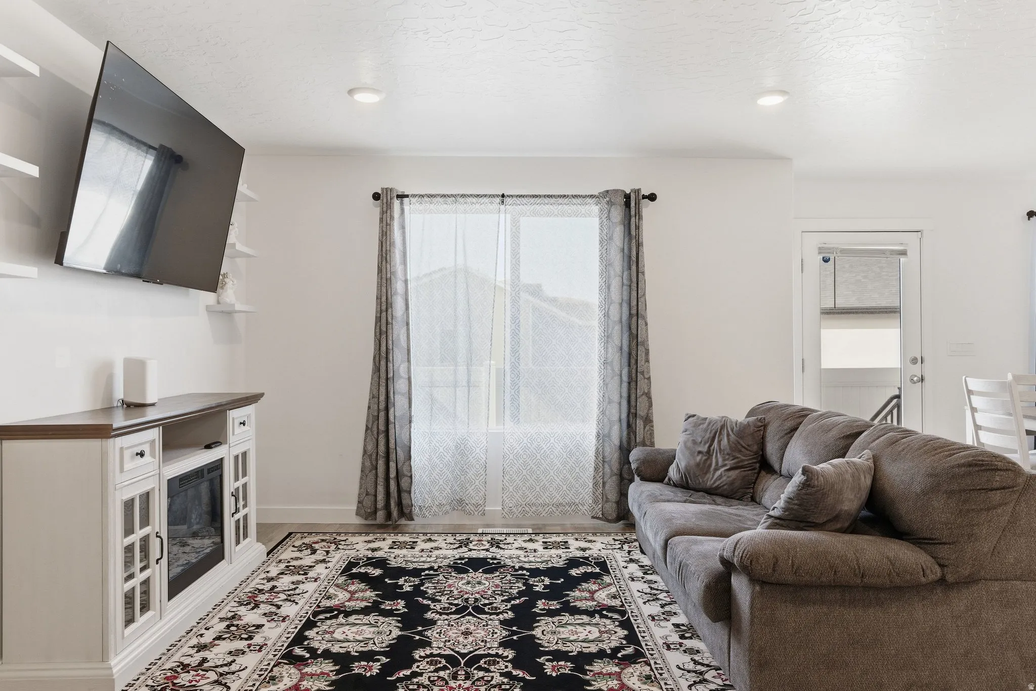 Living area featuring neutral wall tones, recessed lighting, and a large window with sheer and blackout curtains