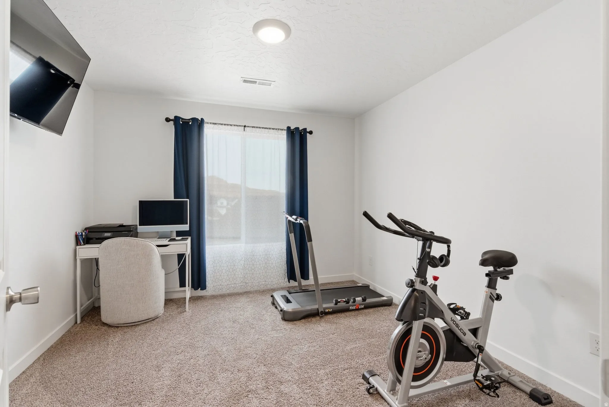 Carpeted room with a window featuring navy blue curtains, white baseboards, and a flush-mount ceiling light fixture