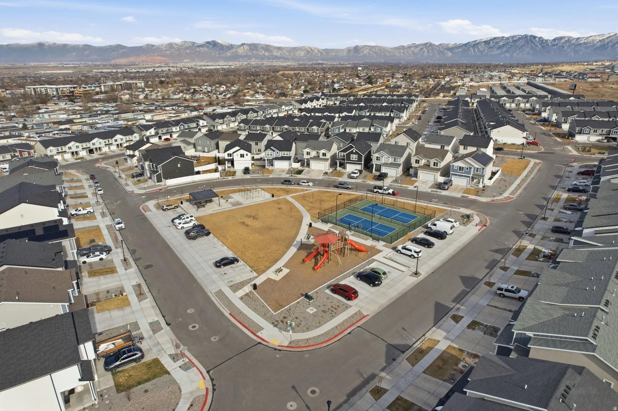 Community green space featuring a playground, two tennis courts, and a covered picnic area