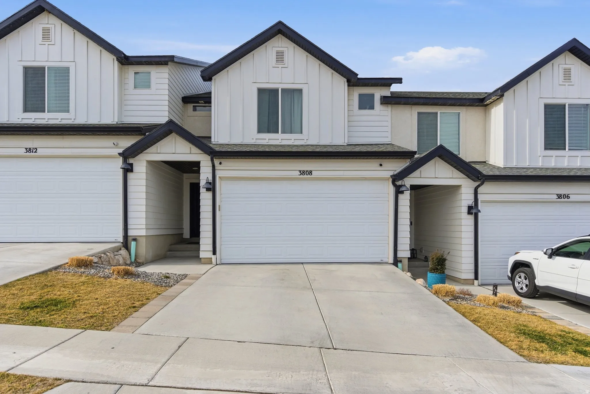 Modern townhome exterior featuring white vertical siding and dark trim accents