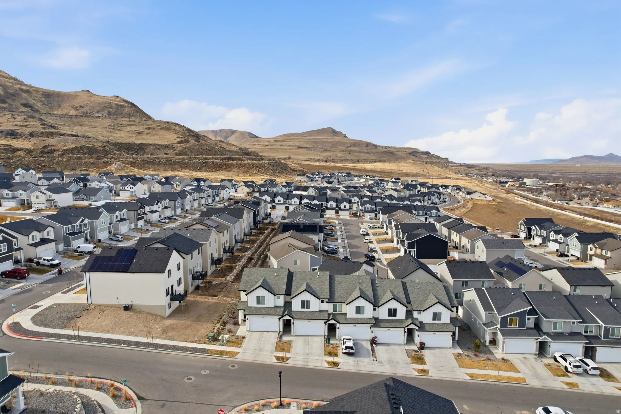 Expansive residential development featuring multiple detached homes and townhomes, distinct architectural styles, and attached garages