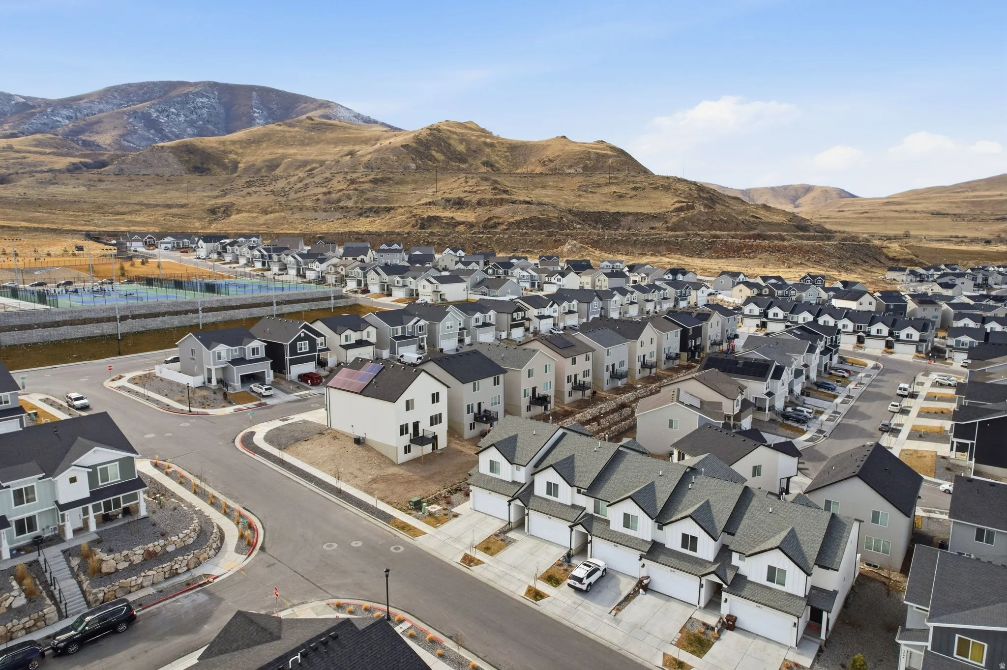 New construction neighborhood featuring multiple two-story homes with attached garages, paved streets, and a backdrop of mountains