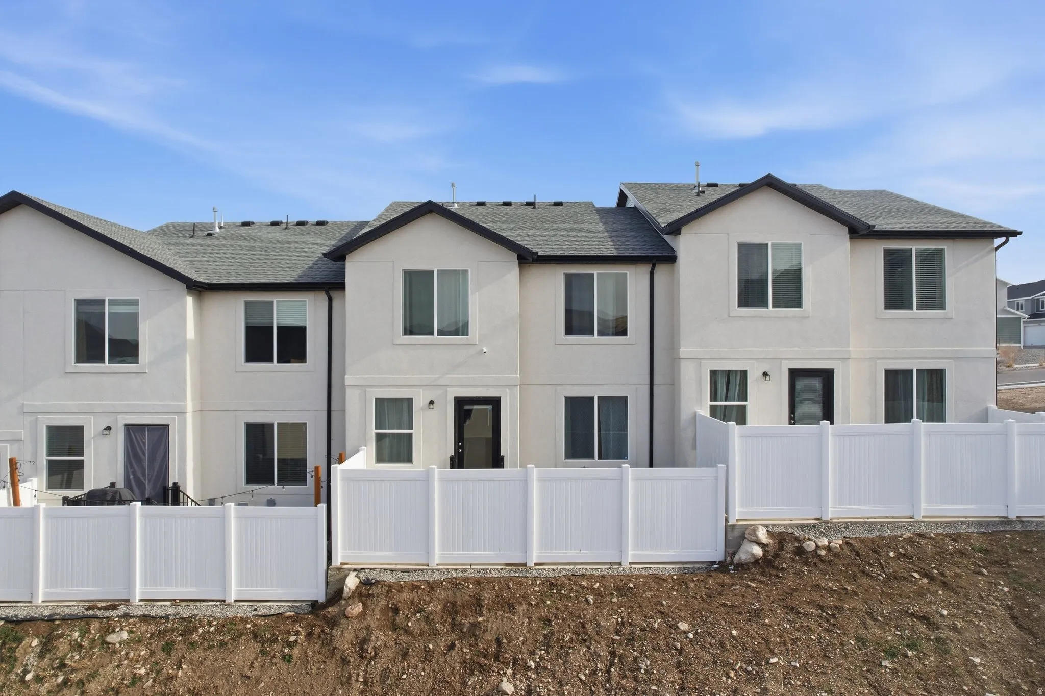 Contemporary townhome exteriors featuring light-colored stucco, dark trim, and prominent windows across two stories