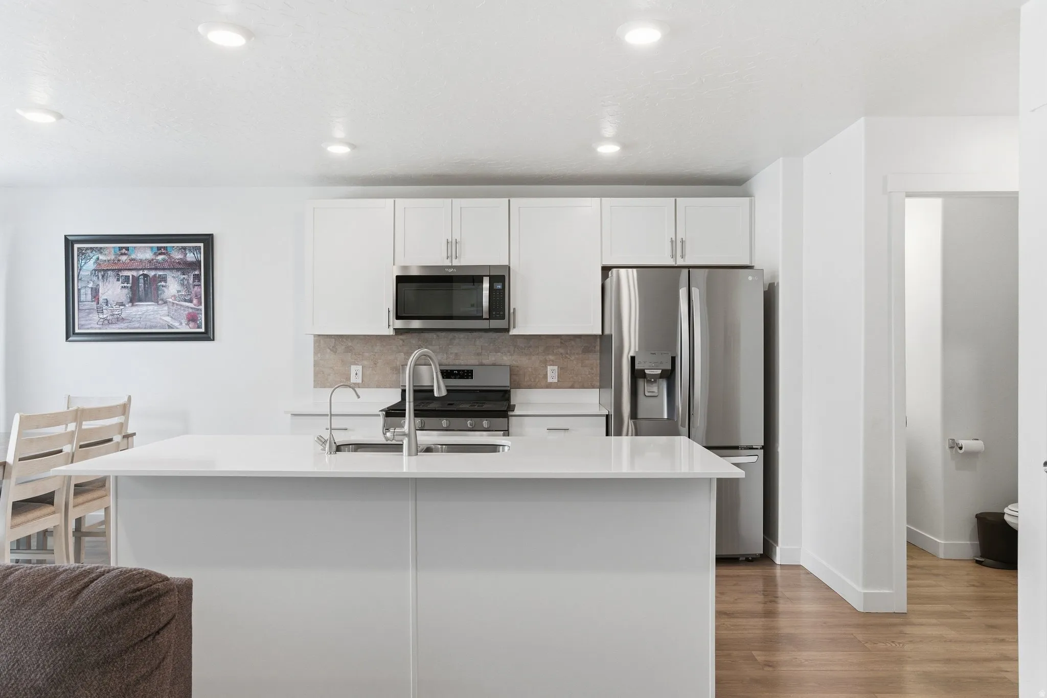 Modern kitchen featuring a large island with an undermount sink and gooseneck faucet