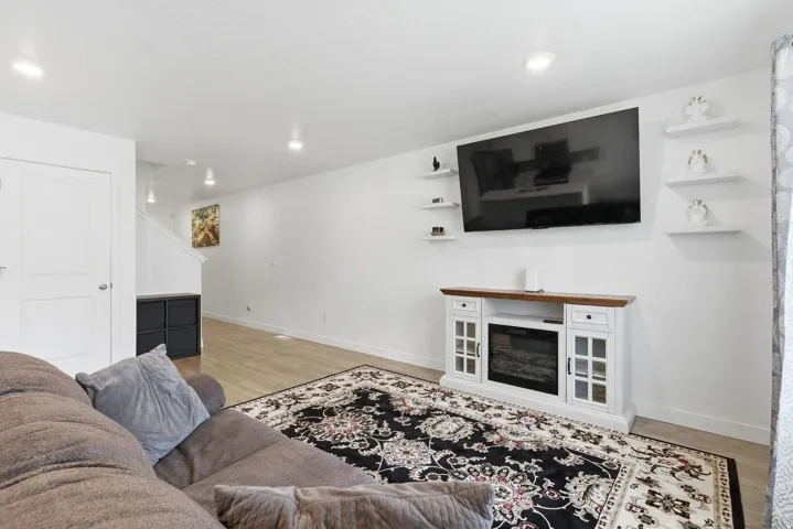 Bright living area featuring wood-finish flooring, recessed lighting, and a white decorative fireplace console with a wooden top