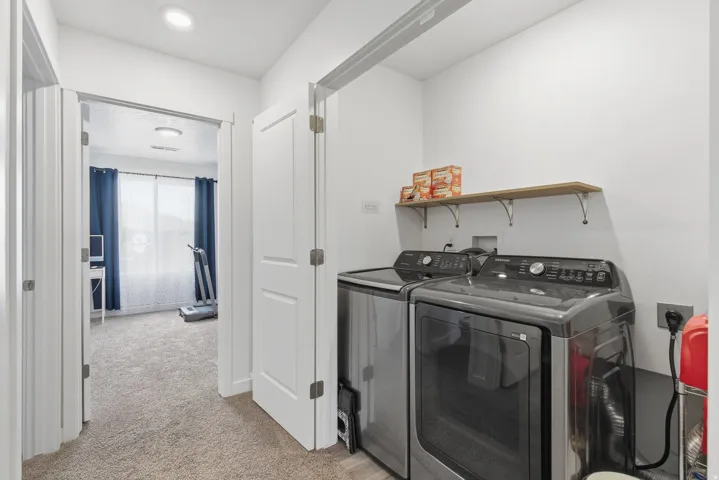 Dedicated laundry area featuring a light wood shelf with decorative brackets, and contemporary white walls