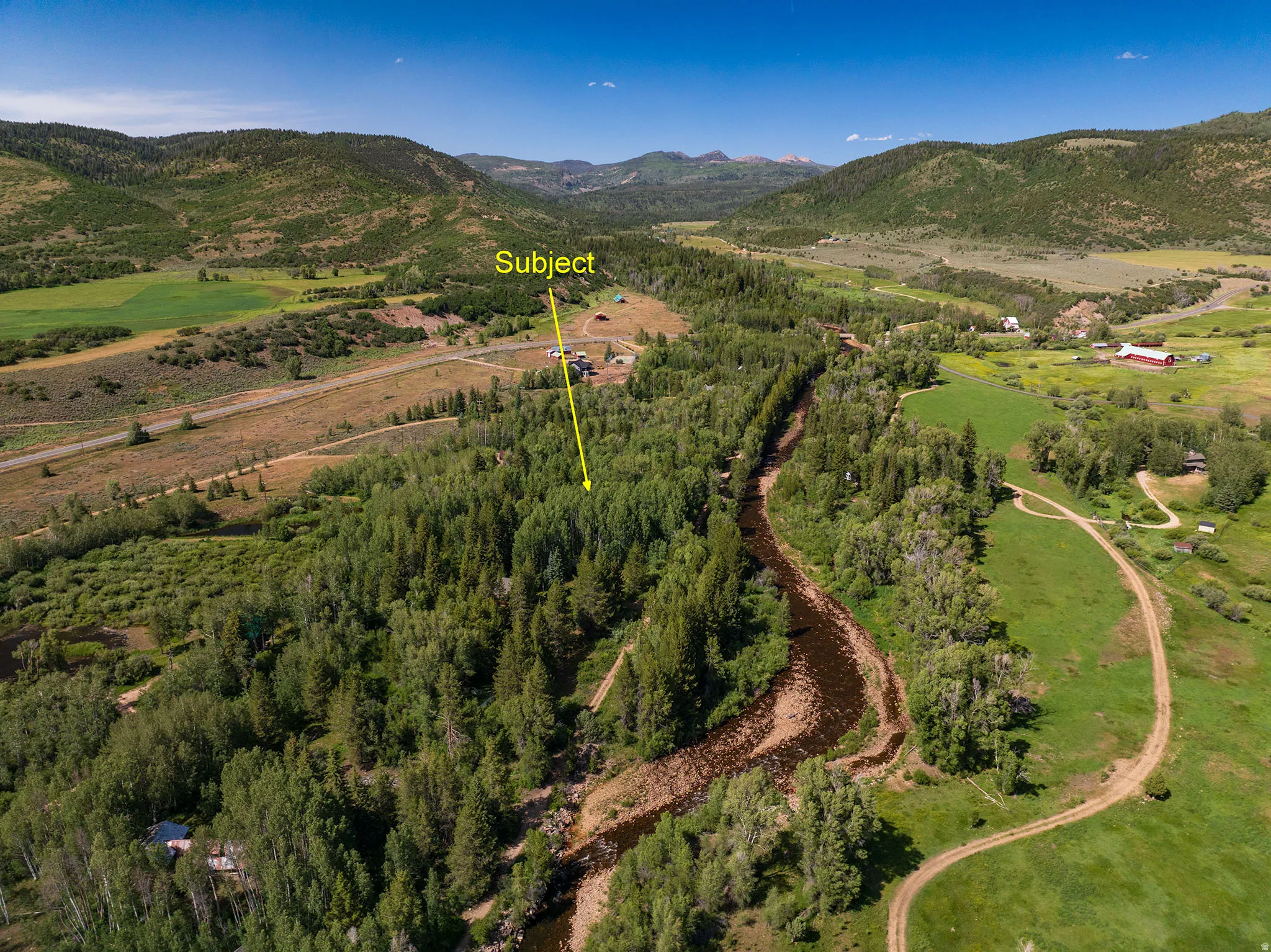 Expansive rural property featuring a winding river, mature trees, and mountainous terrain
