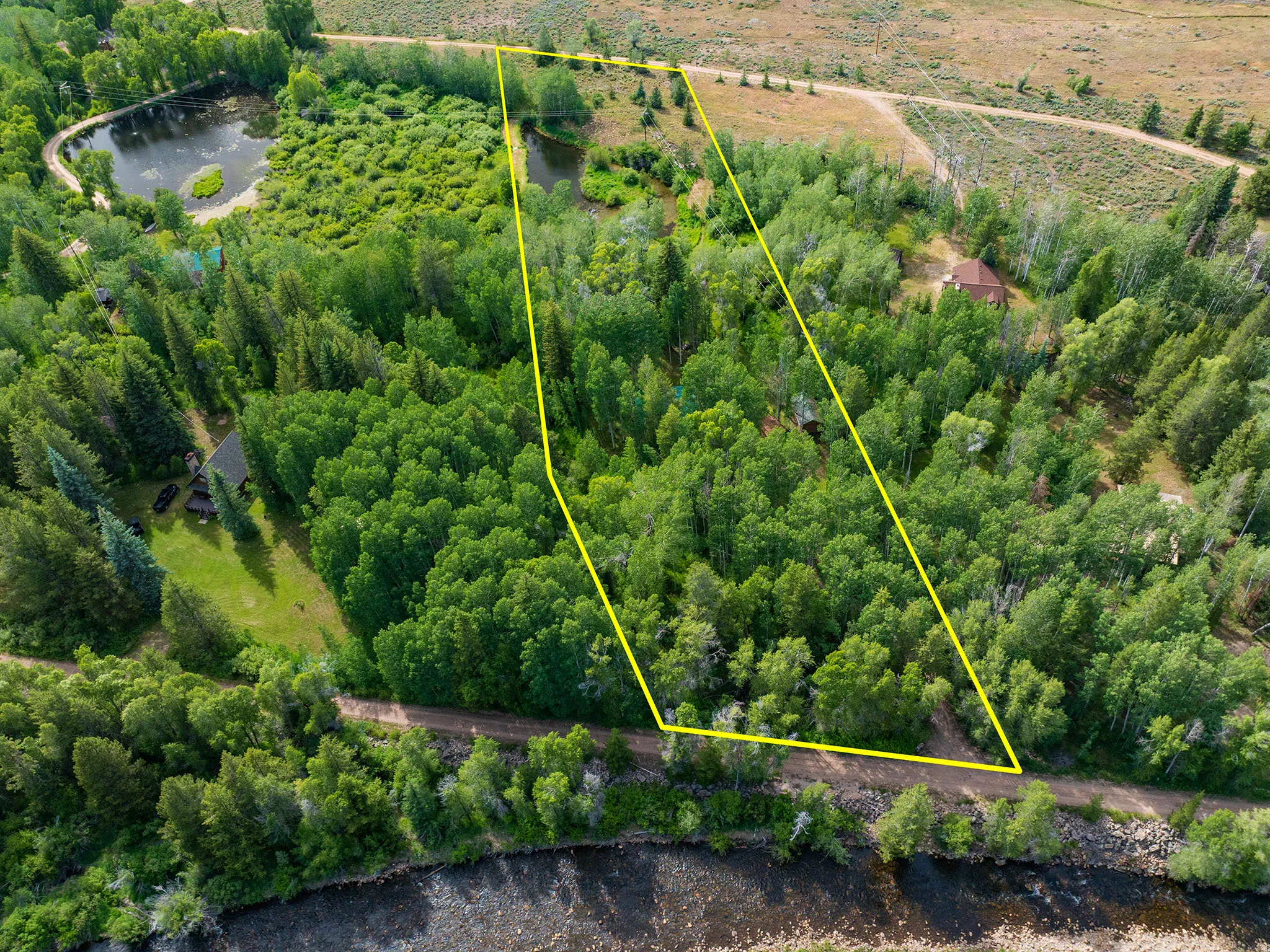 Expansive acreage bordered by a dirt road and water features