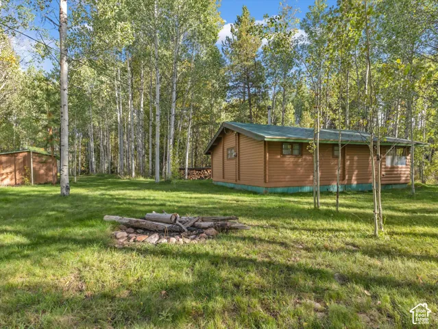 Log cabin exterior with a green roof, surrounded by mature trees