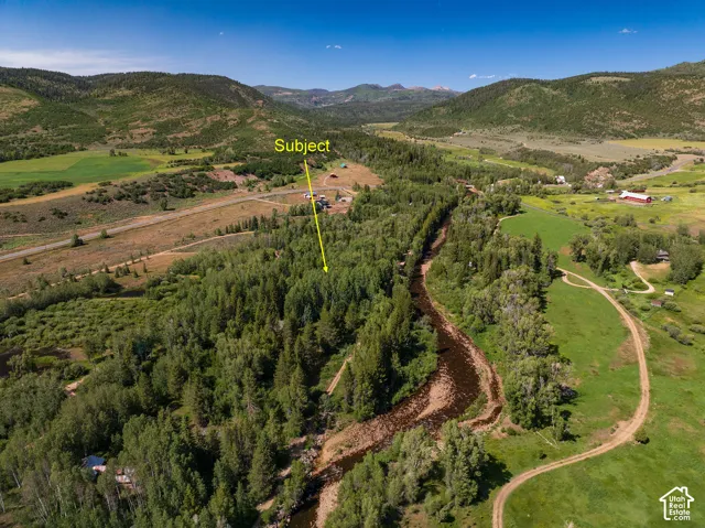 Expansive rural property featuring a winding river, mature trees, and mountainous terrain