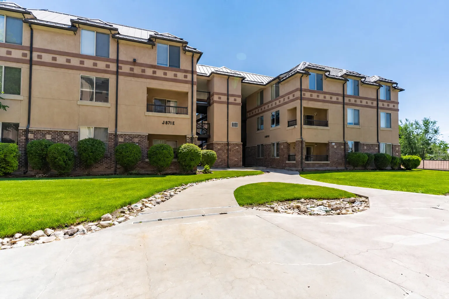Multi-story building featuring stucco siding, stone accents, and a distinctive roofline