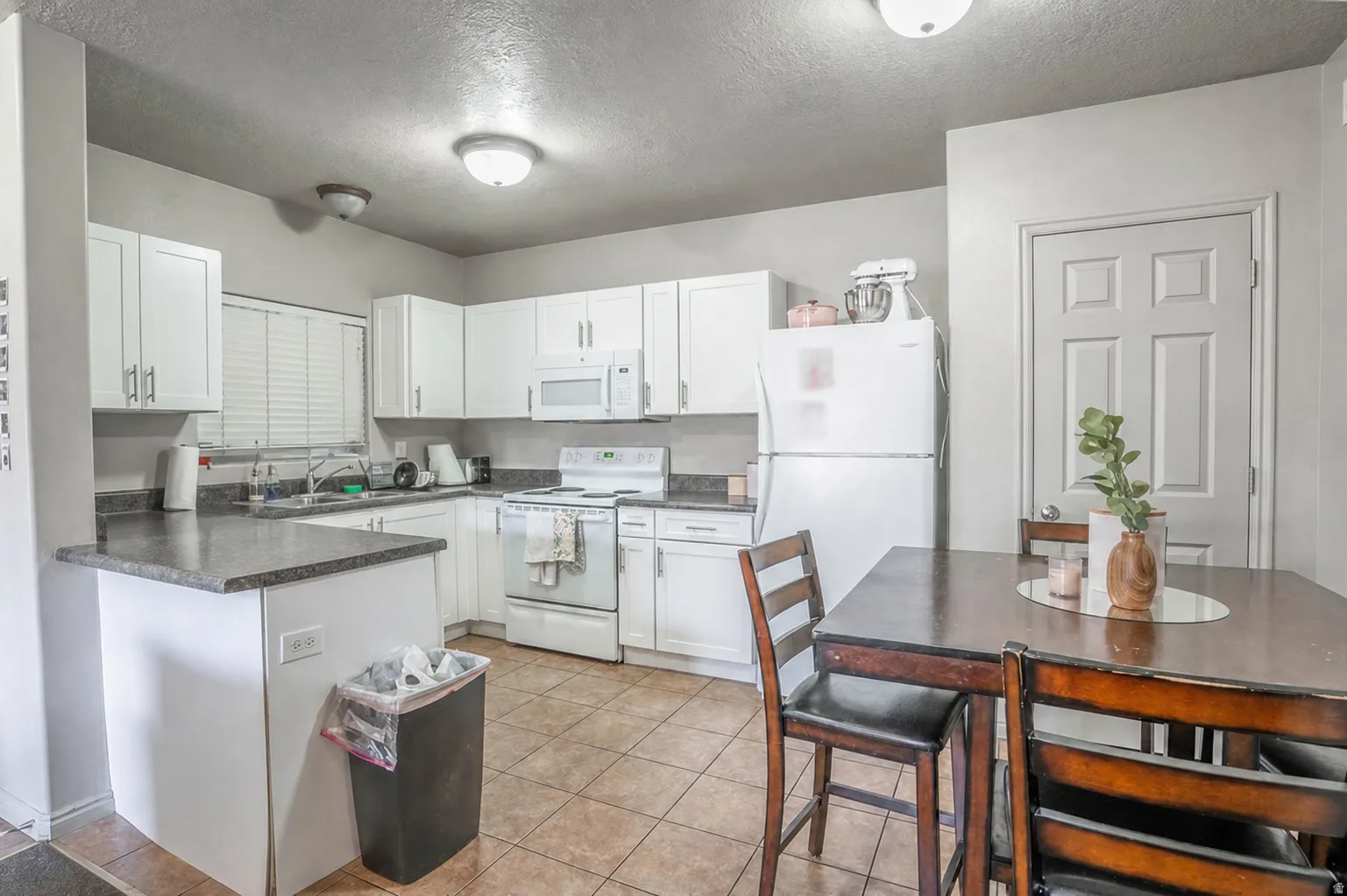 Kitchen featuring white cabinetry, dark countertops, a built-in microwave, and a white range