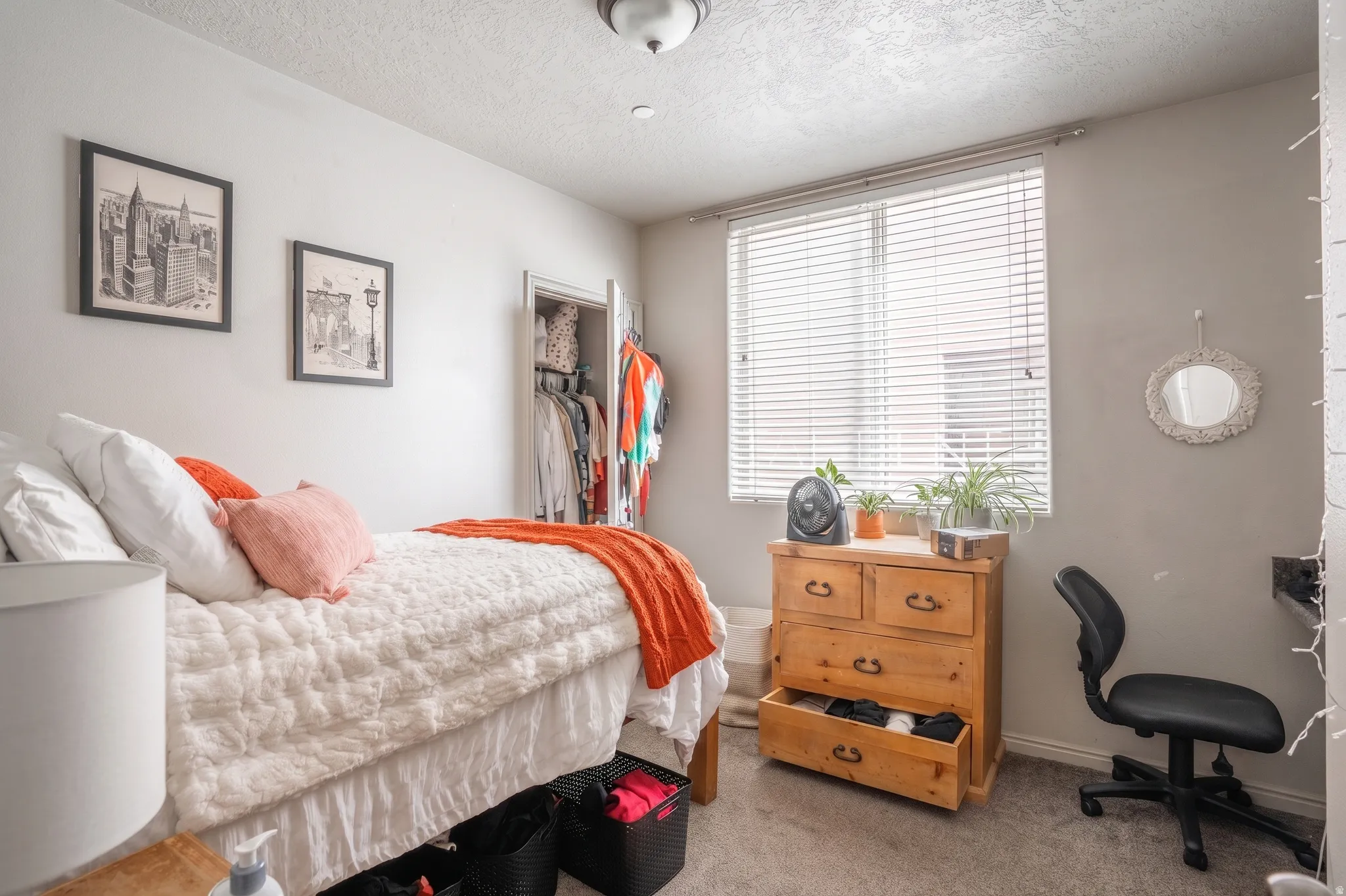 Carpeted bedroom featuring a double window with blinds, ceiling light fixture, and a built-in closet with double doors
