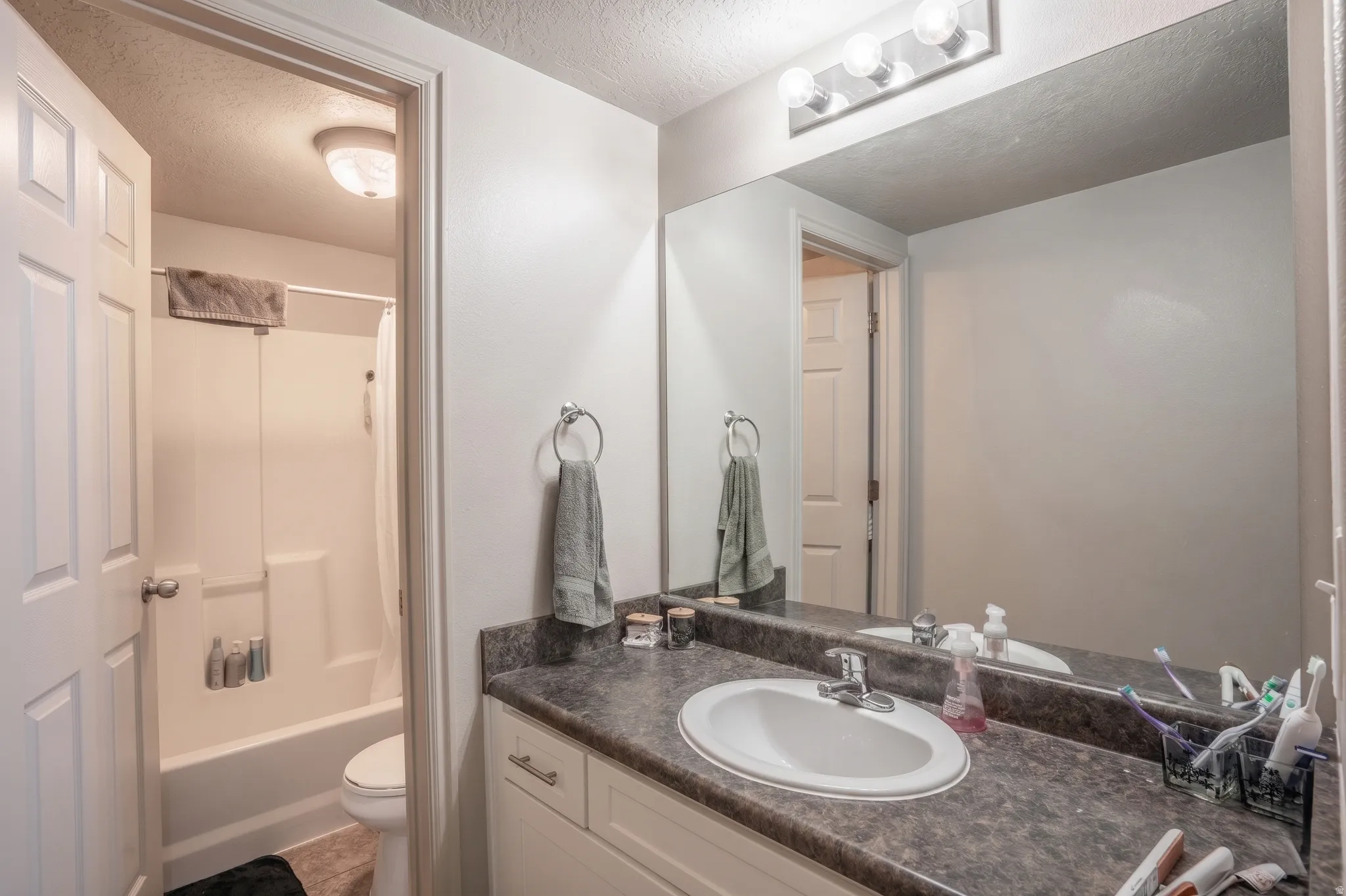 Bathroom vanity featuring an integrated sink, dark laminate countertop, and white cabinetry