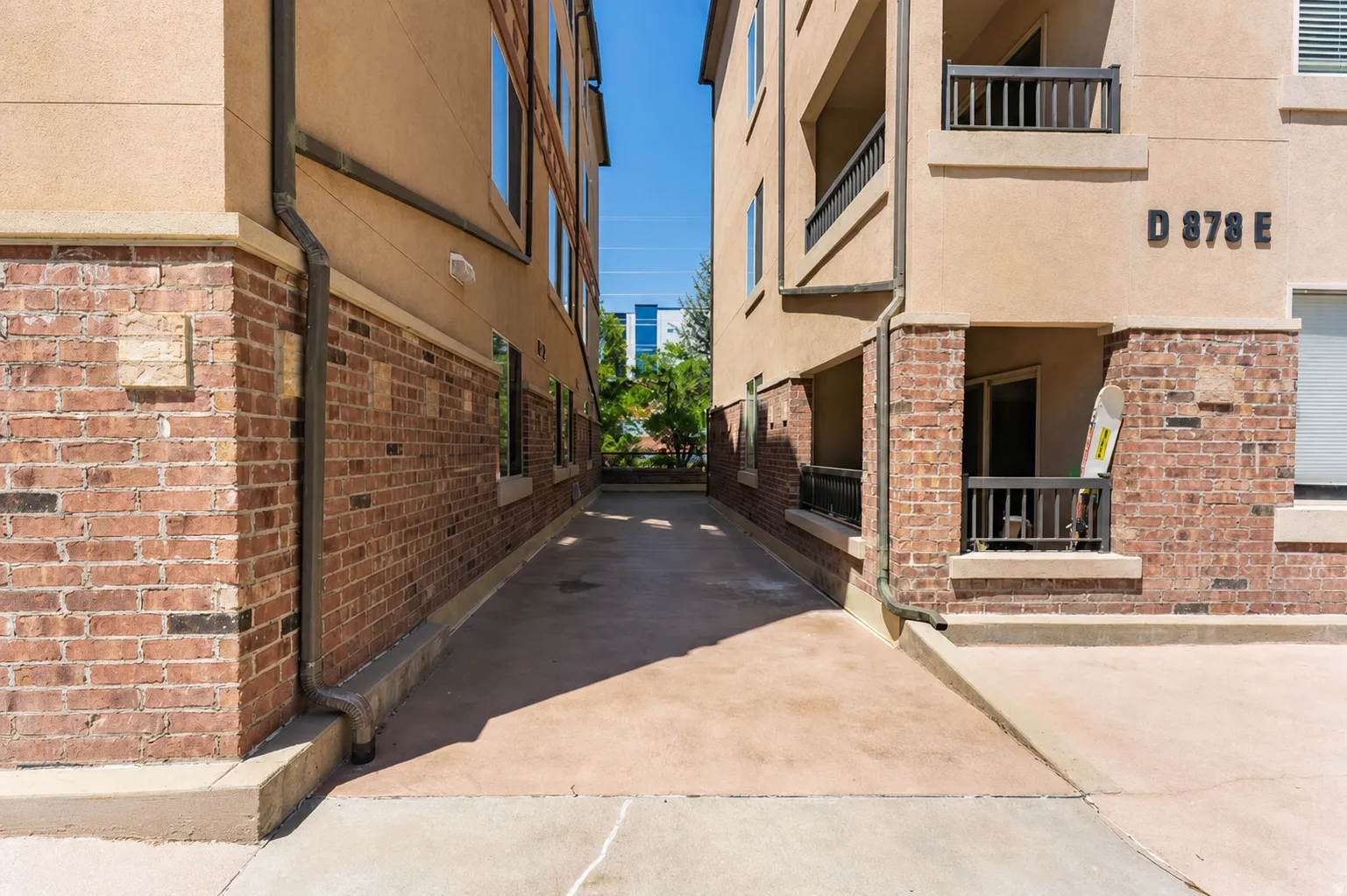 Exterior brick and stucco facade featuring ground-level patios and upper-story balconies