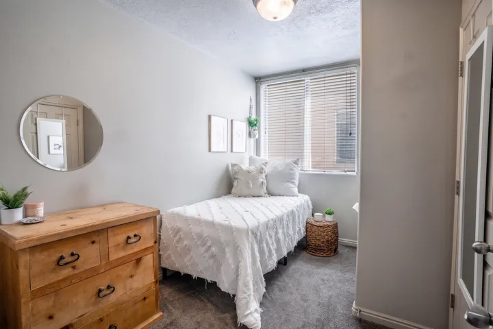 Bedroom featuring neutral wall paint, a window with blinds, carpet flooring, and a flush-mount ceiling light fixture