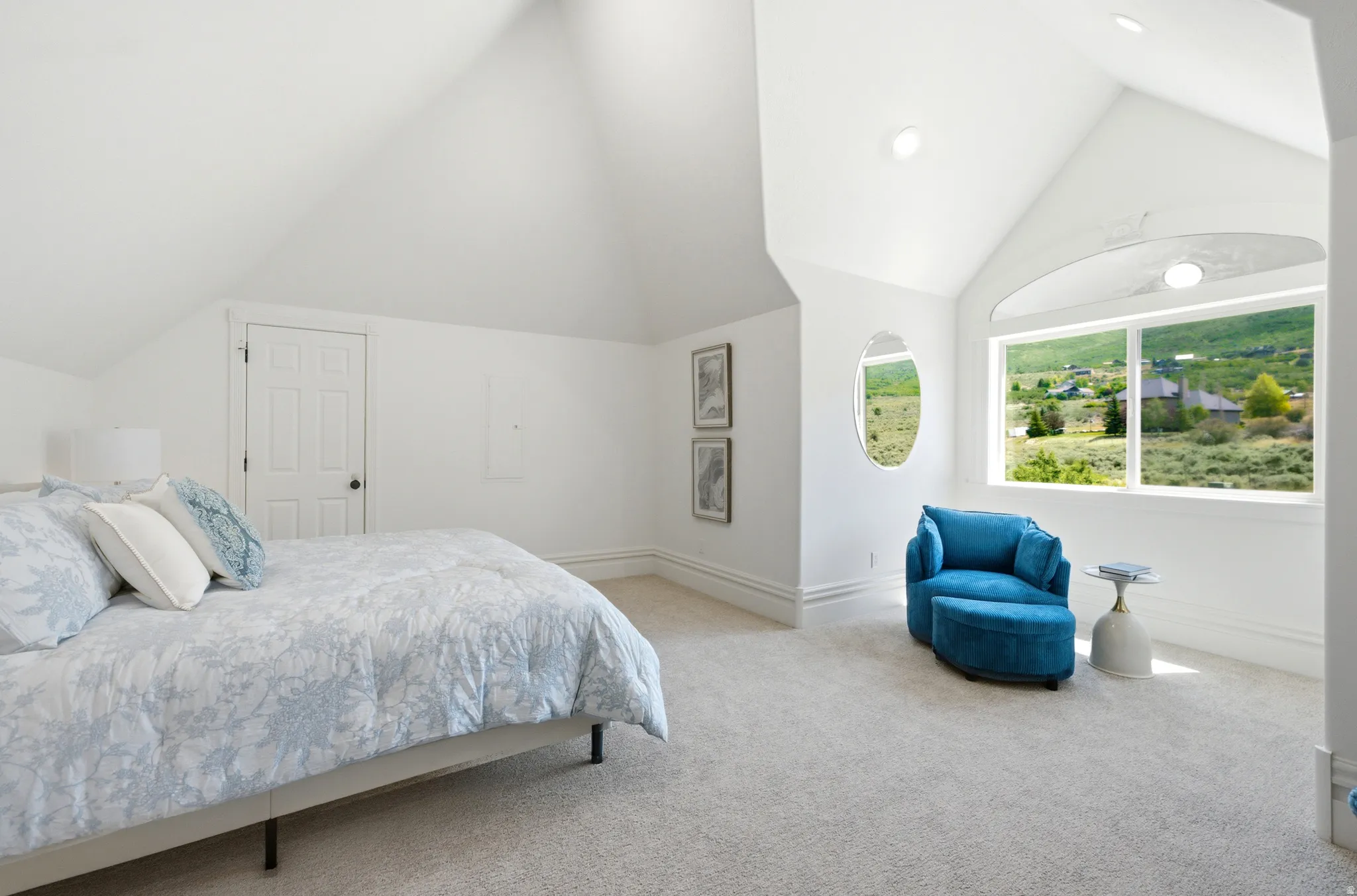 Vaulted white ceilings featuring recessed lighting, a large picture window, and a secondary oval window