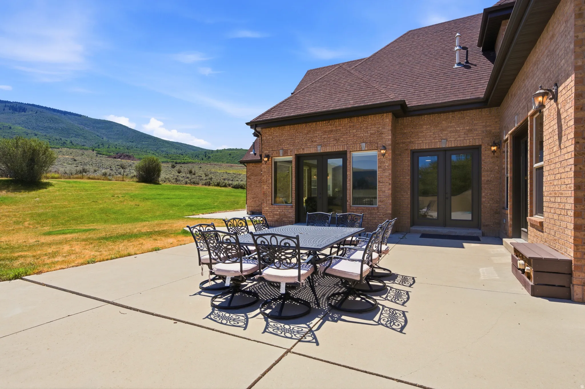 Expansive concrete patio with direct access to interior spaces through multiple French doors