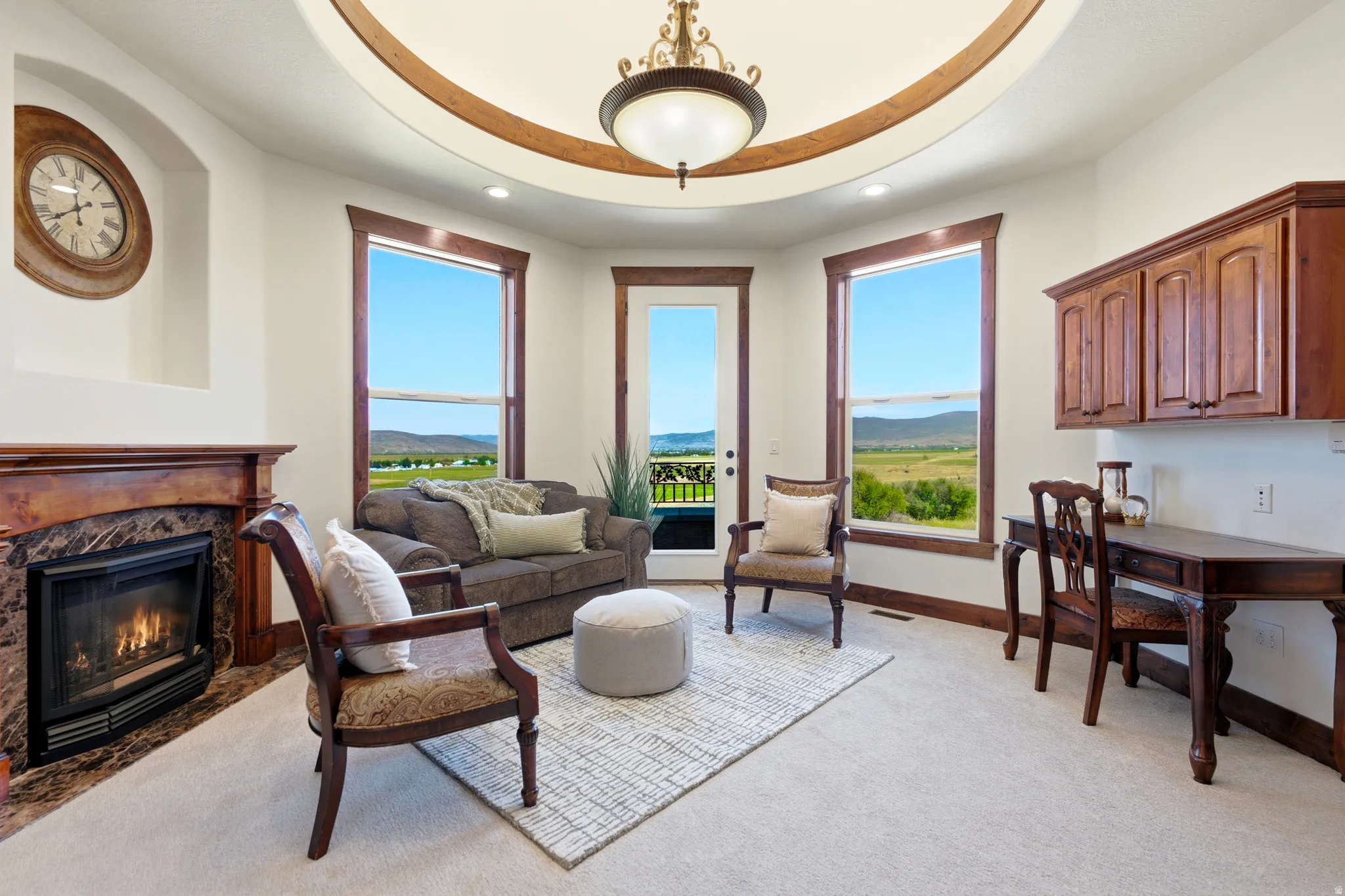 Living area featuring a tray ceiling with wood trim, a central chandelier, and recessed lighting
