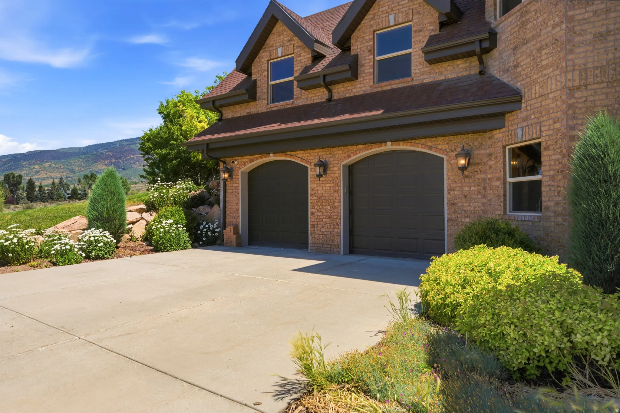 Brick exterior featuring two arched garage doors with wall-mounted lanterns